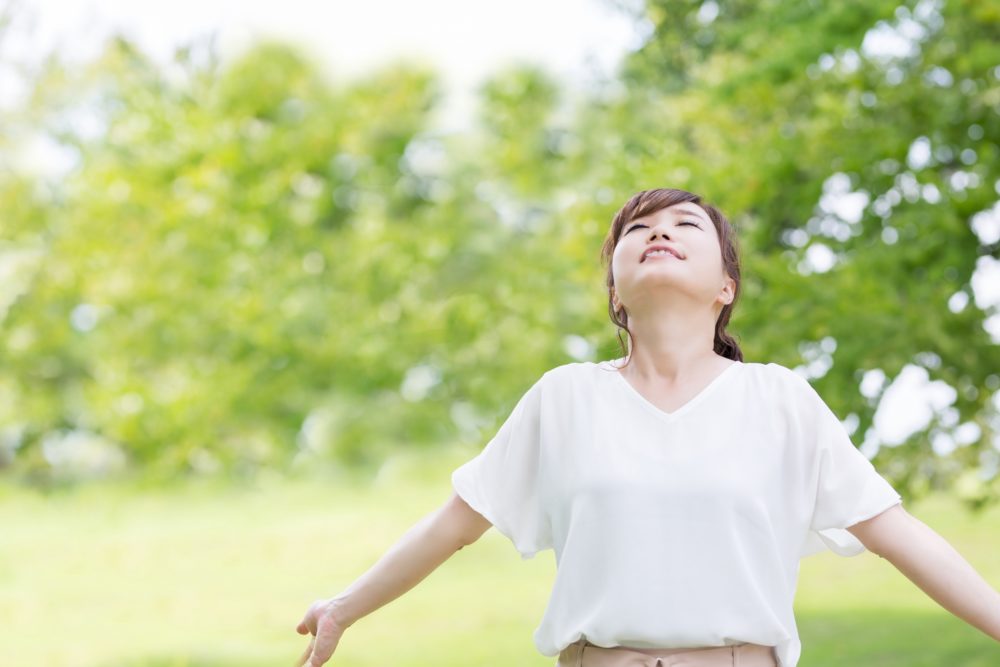 腕を広げ深呼吸する女性